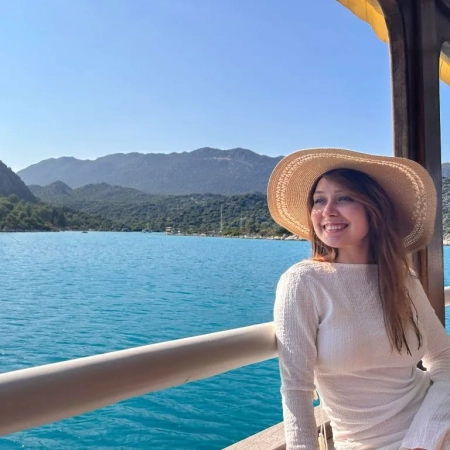 A woman enjoying the view on a gulet during the Fethiye to Kekova and Back cruise, with turquoise sea and green mountains in the background