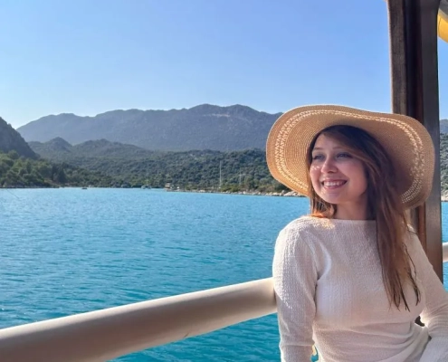 A woman enjoying the view on a gulet during the Fethiye to Kekova and Back cruise, with turquoise sea and green mountains in the background