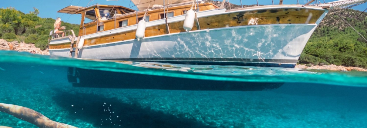 Woman snorkeling near a traditional gulet during the Fethiye to Marmaris and Back cruise, showcasing clear turquoise water and scenic coastal views