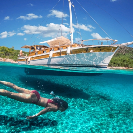 Woman snorkeling near a traditional gulet during the Fethiye to Marmaris and Back cruise, showcasing clear turquoise water and scenic coastal views