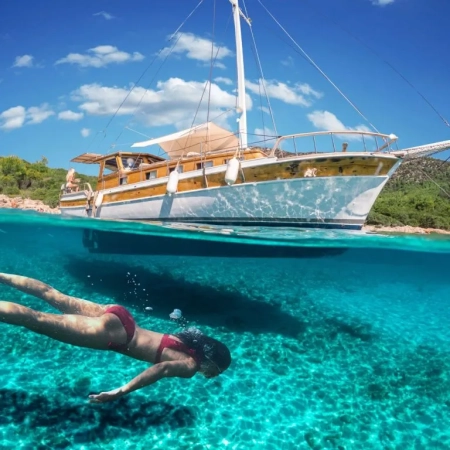 Woman snorkeling near a traditional gulet during the Fethiye to Marmaris and Back cruise, showcasing clear turquoise water and scenic coastal views