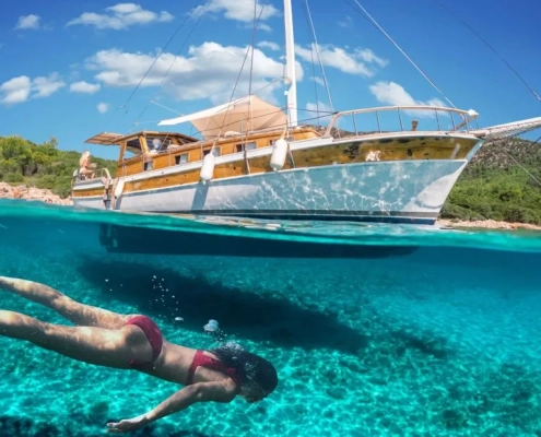 Woman snorkeling near a traditional gulet during the Fethiye to Marmaris and Back cruise, showcasing clear turquoise water and scenic coastal views