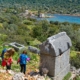 Hikers trekking along the Lycian Way, passing ancient Lycian rock tombs with a stunning view of the Mediterranean coastline in the background.