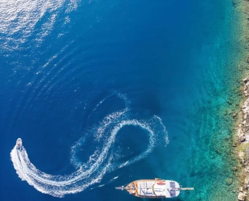 Aerial view of a gulet anchored near the coast with a tender boat making a circular trail during the Kemer to Kekova and Back gulet cruise