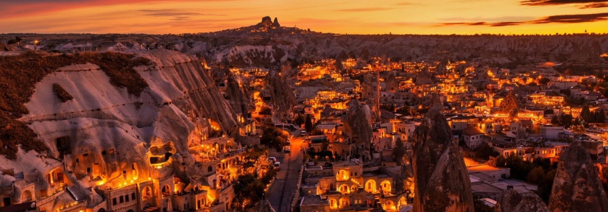 bus-and-sail-turkey-goreme Evening view over illuminated cave hotels and fairy chimneys in Göreme, Cappadocia – a cultural stop featured in Bus and Sail Turkey tours.